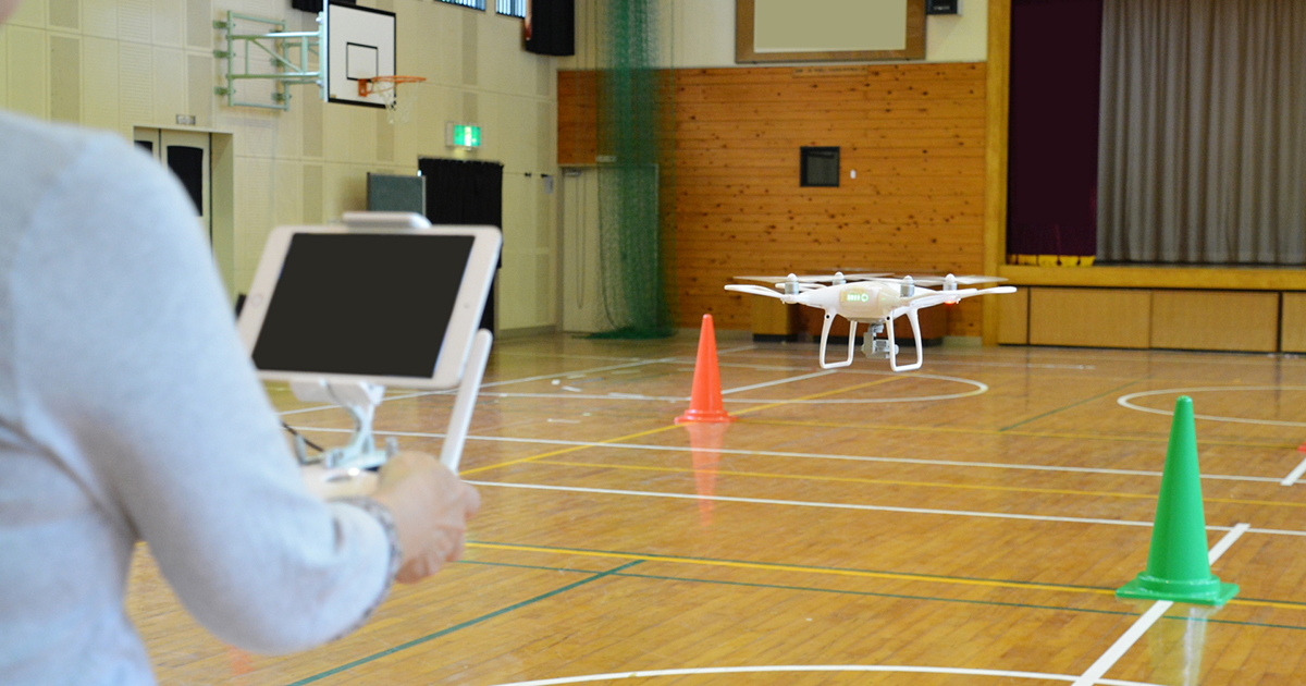 ドローンの操縦練習を体育館で行っている光景